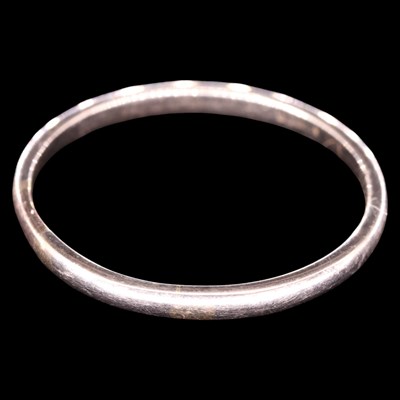 Lot 1318 - A slender white-coloured yellow metal band,...